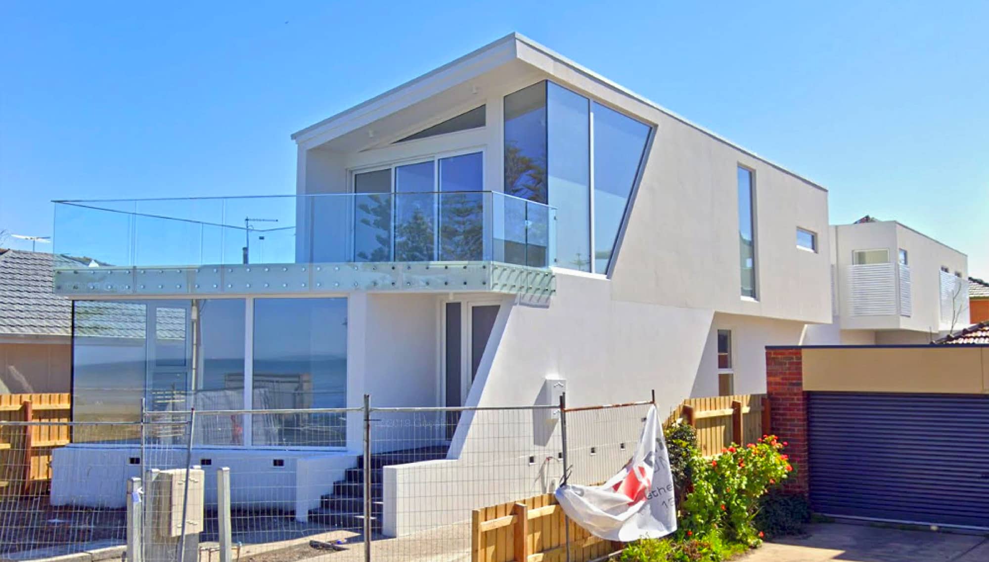 Passive house with white coloured lift and slide doors and shaped butt joint fixed windows