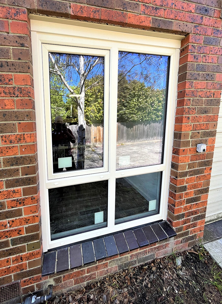 Cream-coloured tilt and turn window mounted on a red brick wall