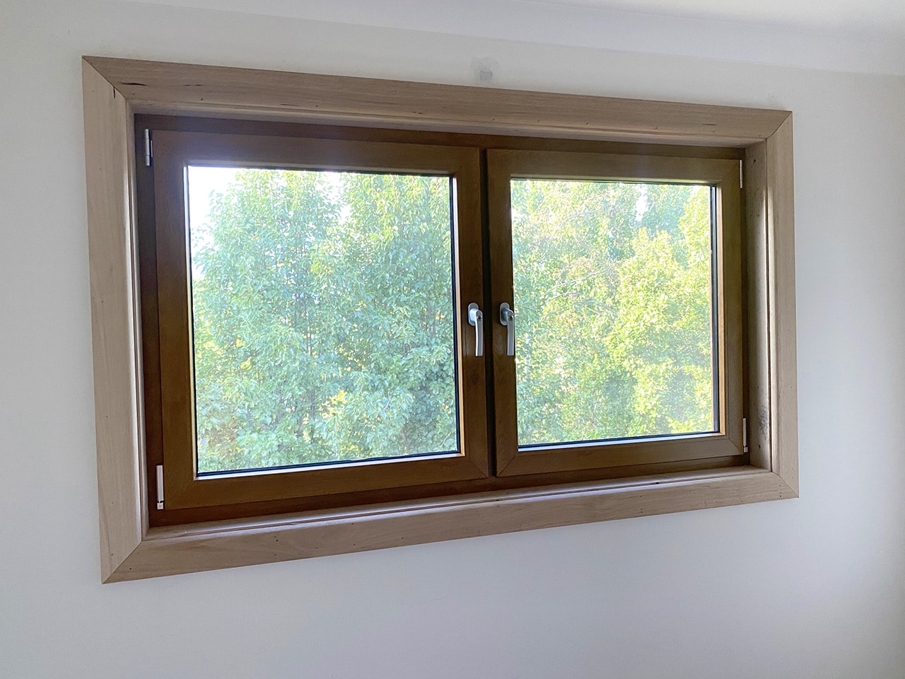 Golden oak coloured tilt and turn window with forest view